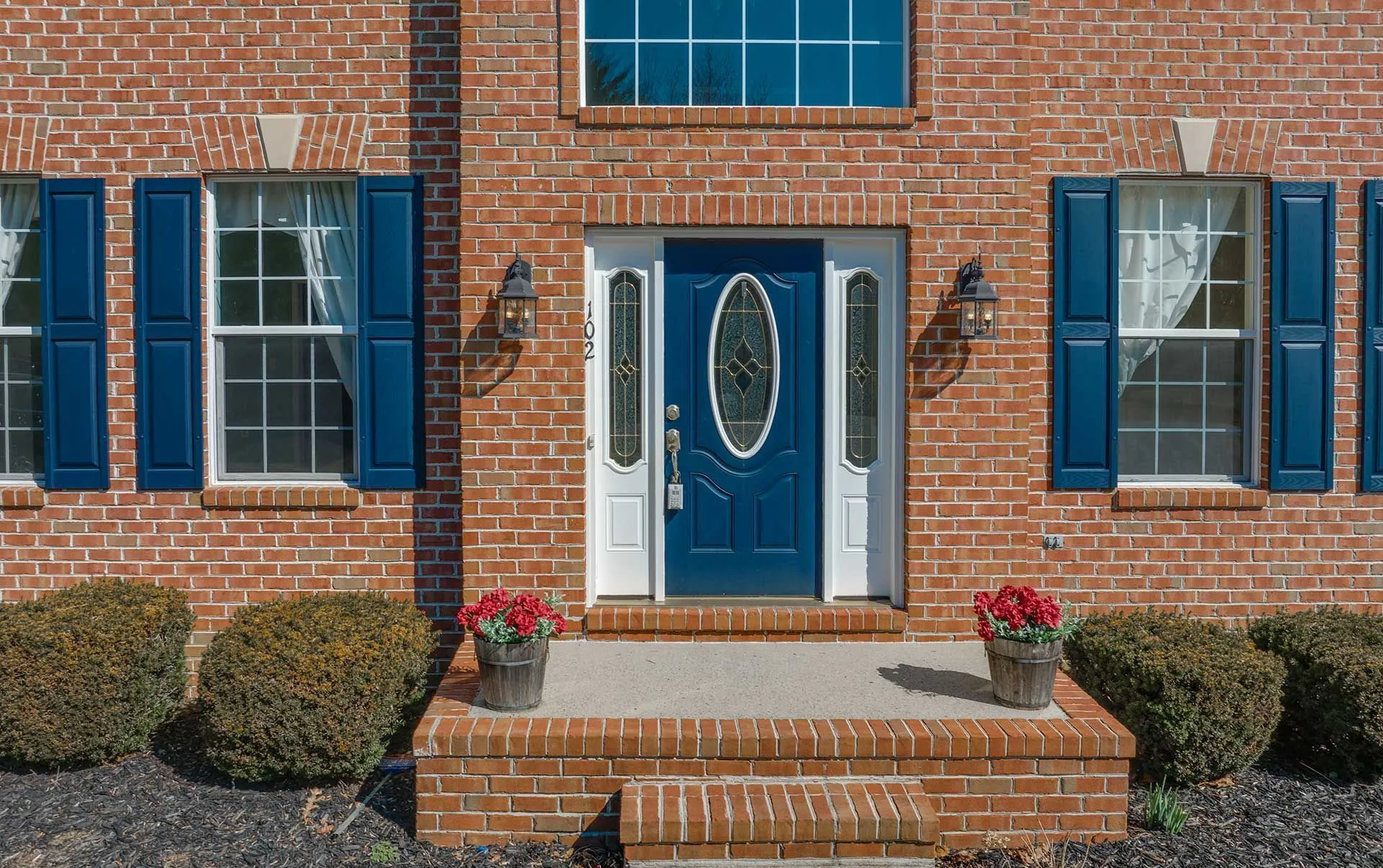 Blue entry door with sidelights on brick